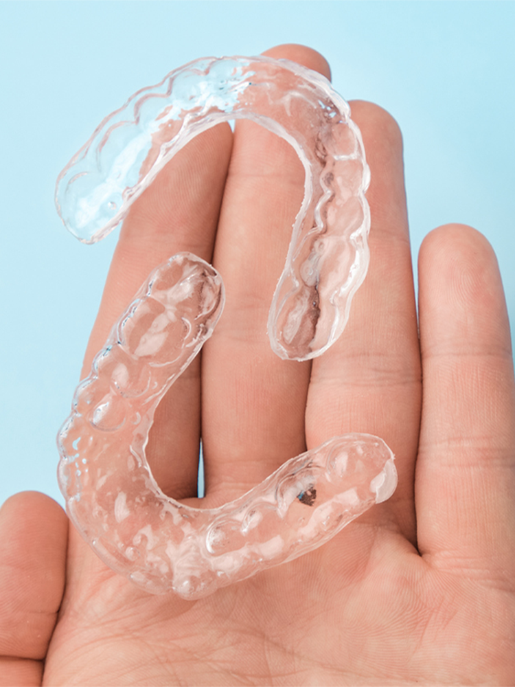 image of a hand holding clear aligner retainers